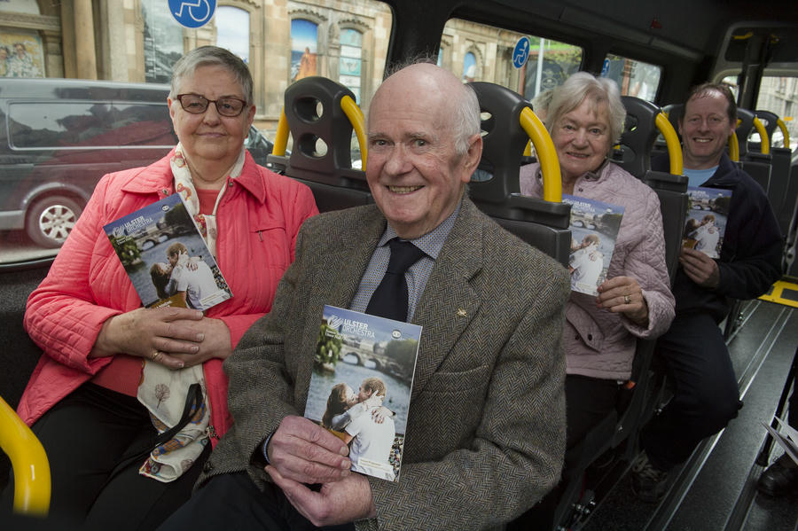 Four older adults sit on a bus, each holding a wedding photo brochure. Smiling and seated in two rows, they look ready to Move to the Music and celebrate joyful moments together.
