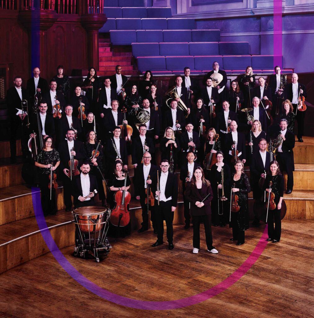 The Ulster Orchestra stand on stage at the Ulster Hall, Belfast with their Chief Conductor Anna Handler.